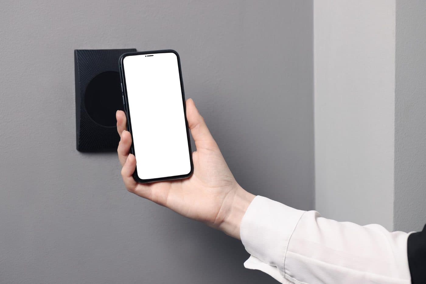 A phone held against a small NFC tag mounted on a wall