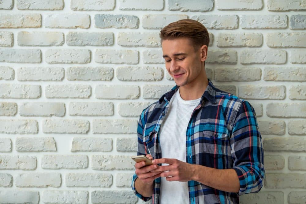 A team member checking their phone while leaning against a wall